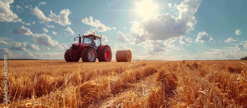 A tractor is actively driving through a wheat field, threshing and baling straw on a sunny day in a rural setting. photo