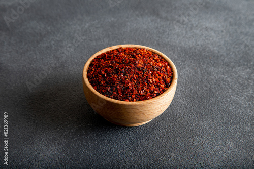 Red pepper flakes.Red chili peppers in wooden bowl on black background
