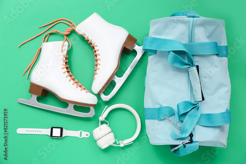 Sport bag with skates and headphones on green background