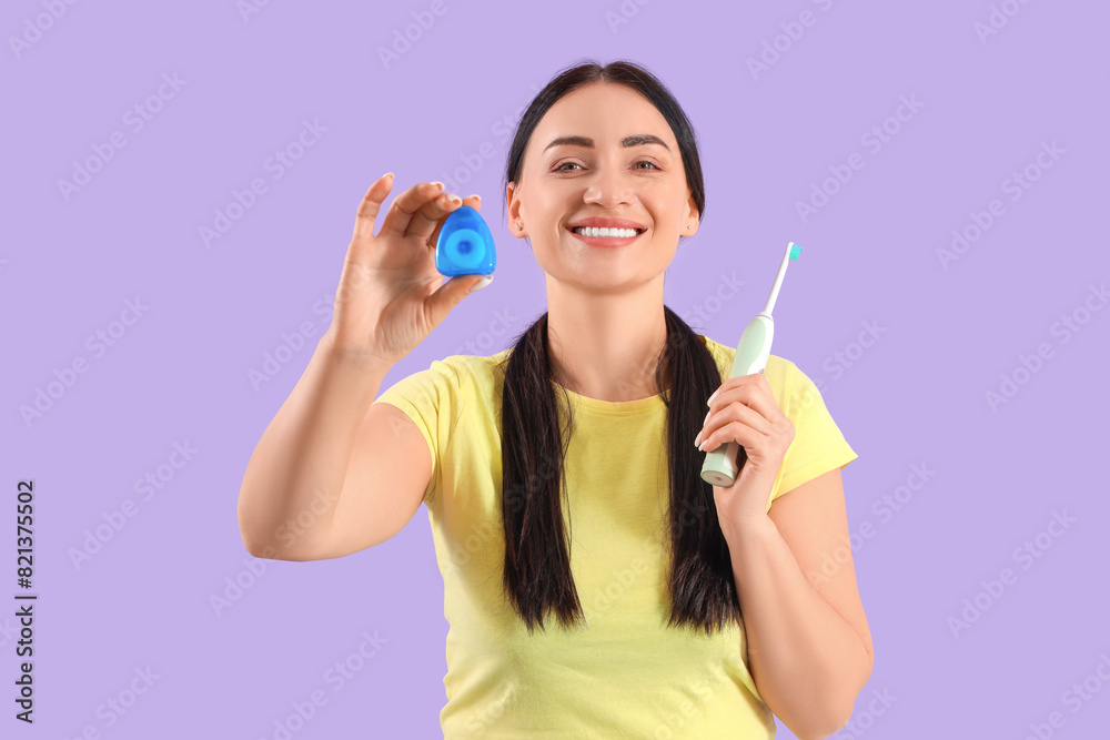 Beautiful young happy woman with dental floss and electric toothbrush on purple background Beautiful young happy woman with dental floss and electric toothbrush on purple background