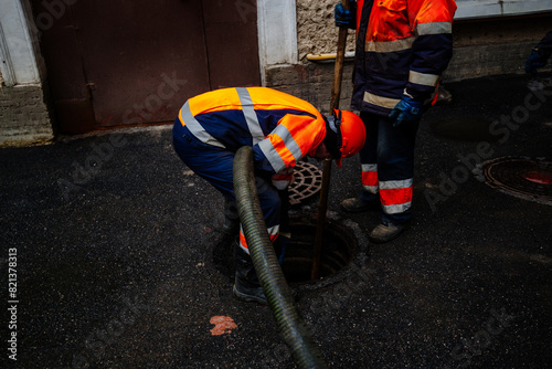 Sewer workers cleaning manhole and unblocking sewers the street sidewalk photo