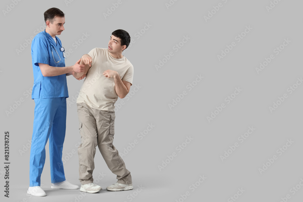 Young man with doctor on light background. National Cerebral Palsy Awareness Month Young man with doctor on light background. National Cerebral Palsy Awareness Month