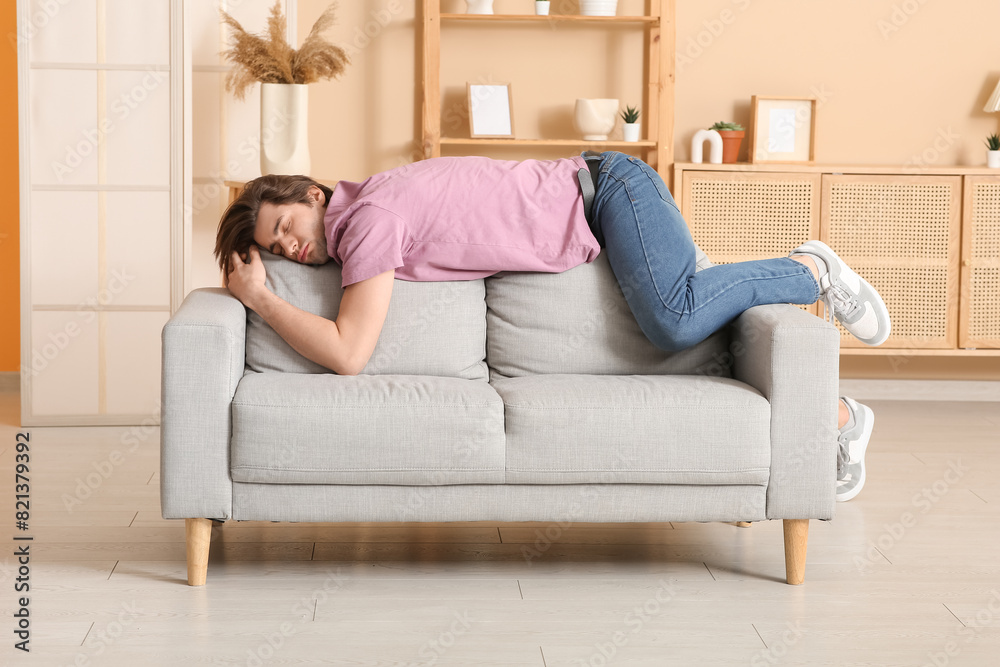 Weary young man sleeping on sofa at home Weary young man sleeping on sofa at home