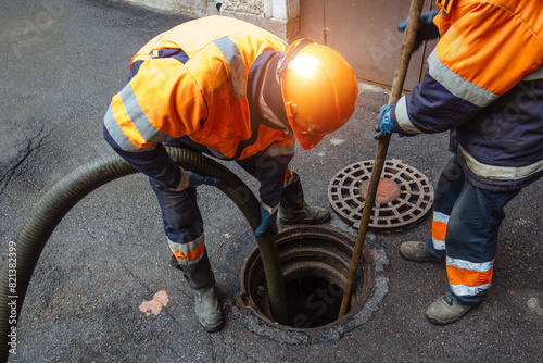 Sewer workers cleaning manhole and unblocking sewers the street sidewalk