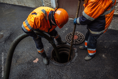 Sewer workers cleaning manhole and unblocking sewers the street sidewalk