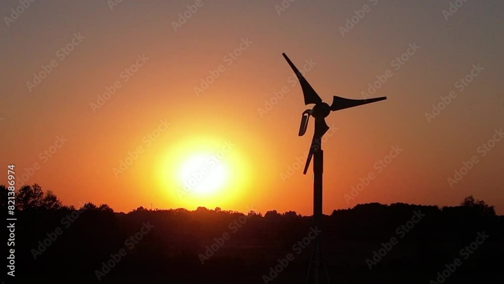 Slowly spinning blades of a wind power generator with decreasing wind against the background of the setting sun - the end of electricity from renewable sources Slowly spinning blades of a wind power generator with decreasing wind against the background of the setting sun - the end of electricity from renewable sources