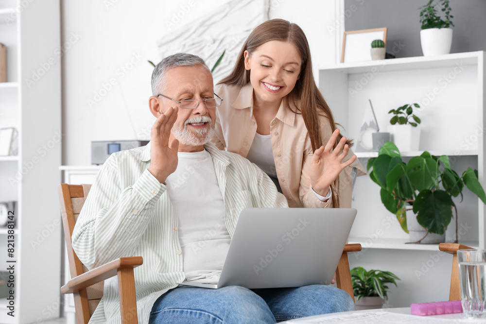 Female caregiver with senior man video chatting in nursing home Female caregiver with senior man video chatting in nursing home