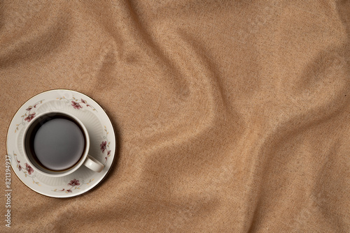 Cup of coffee on fabric background from above. Vintage style. Copy space