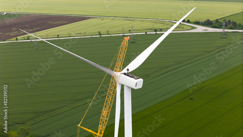 carbon neutral electricity power. Wind turbine repaired by workers, maintenance of turbine with using a crane