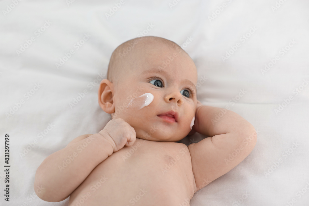 Cute little baby with cream on face on white blanket Cute little baby with cream on face on white blanket