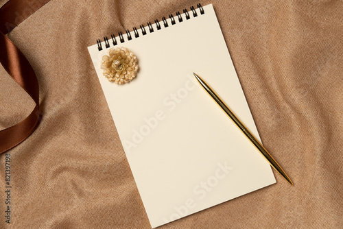 Empty notebook with pen on a fabric background from above. Copy space