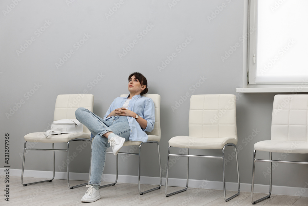 Woman sitting on chair and waiting for appointment indoors Woman sitting on chair and waiting for appointment indoors