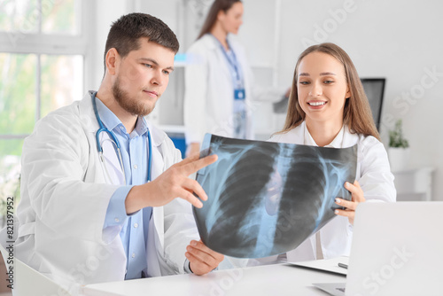Young doctors studying x-ray image of lungs at table in clinic