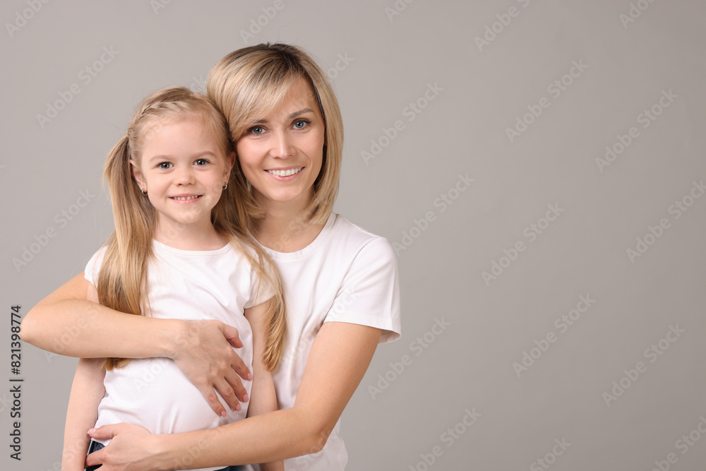 Family portrait of happy mother and daughter on grey background. Space for text Family portrait of happy mother and daughter on grey background. Space for text