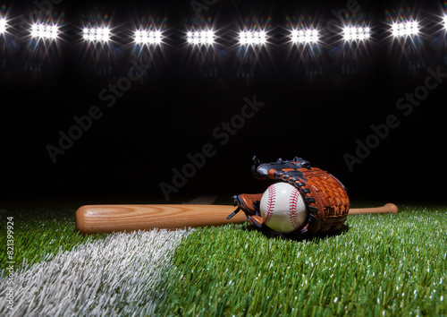 Canvas Print Baseball batt glove and ball low angle on grass field with stripe below lights a