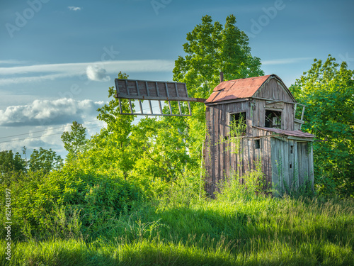 Abandoned wooden windmill in green bushes in spring day