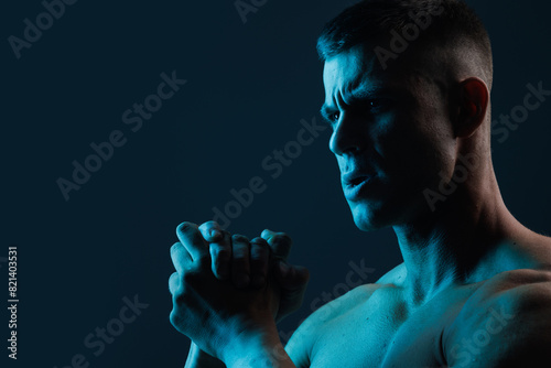 Muscular model sports young man on dark background. Fashion portrait of strong brutal guy. Male flexing his muscles.
