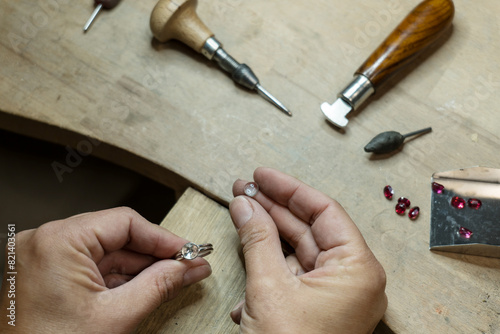 Stonesetter examining a blue transparent stone before fixing in bezel setting of the silver ring