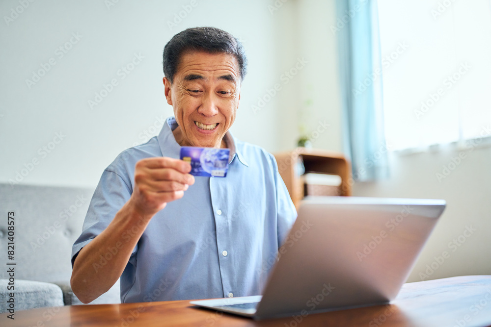 ネットショッピングでクレジットカード番号を打ち込むシニア男性 ネットショッピングでクレジットカード番号を打ち込むシニア男性