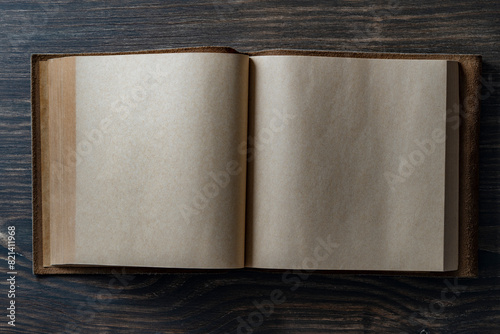 Opened empty vintage book in leather cover on wooden background, space for text, closeup, top view, copy space