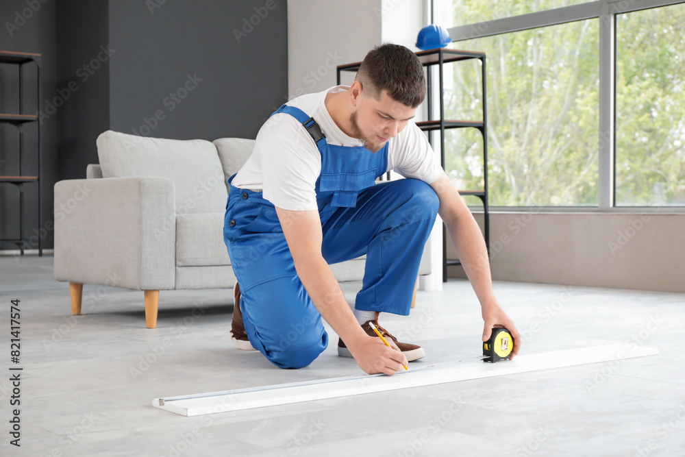 Male contractor measuring plank in room