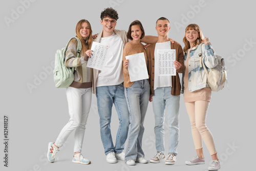 Group of students with results of exam on light background