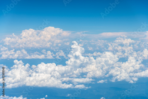 Unique aerial view of bodies of cumulus clear white clouds towers in bright blue sky background.