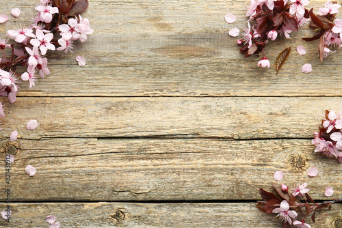 Spring branches with beautiful blossoms and leaves on wooden table, flat lay. Space for text
