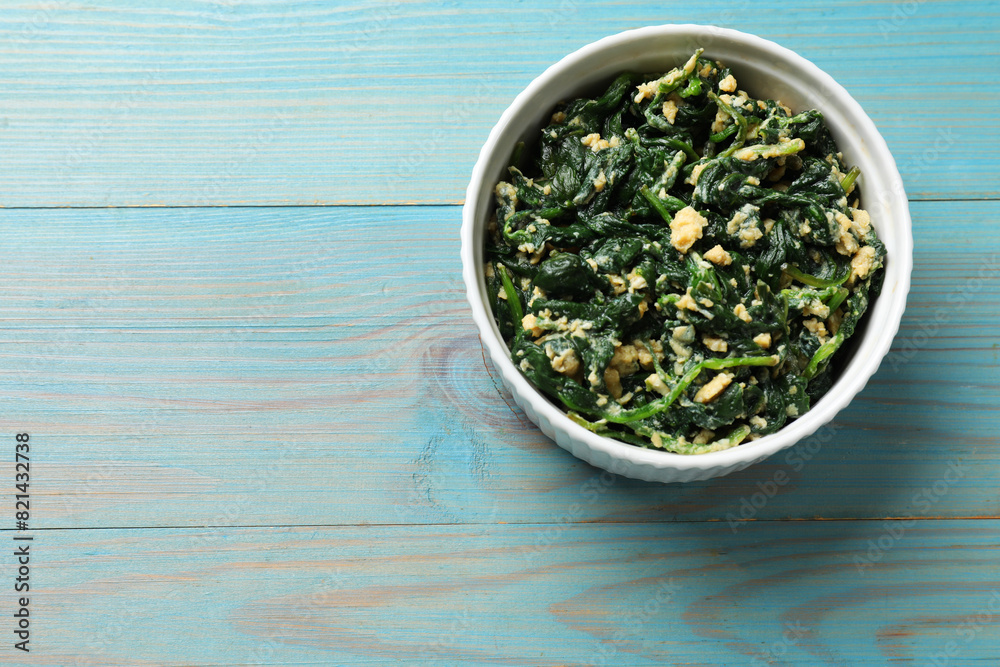 Tasty spinach dip with egg in bowl on light blue wooden table, top view. Space for text Tasty spinach dip with egg in bowl on light blue wooden table, top view. Space for text