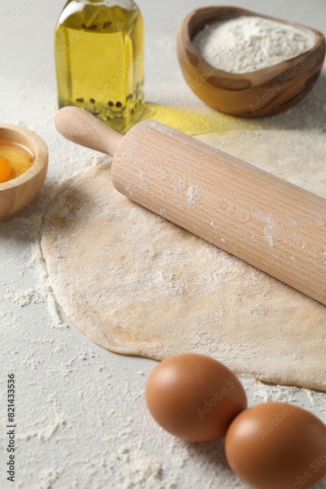 Raw dough, rolling pin and ingredients on table Raw dough, rolling pin and ingredients on table