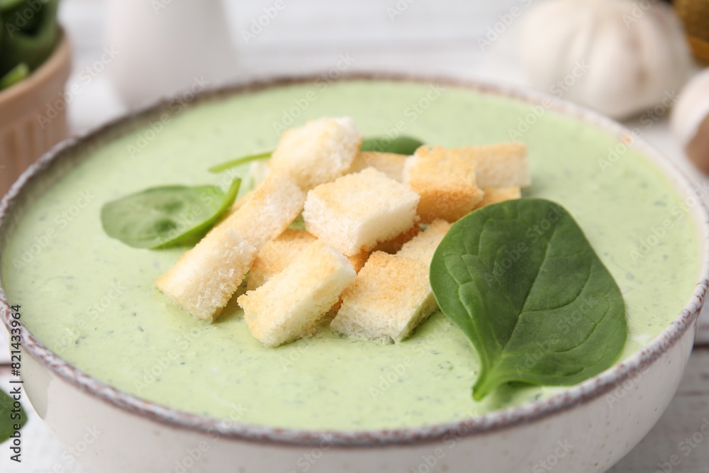 Delicious spinach cream soup with leaves and croutons in bowl on table, closeup Delicious spinach cream soup with leaves and croutons in bowl on table, closeup