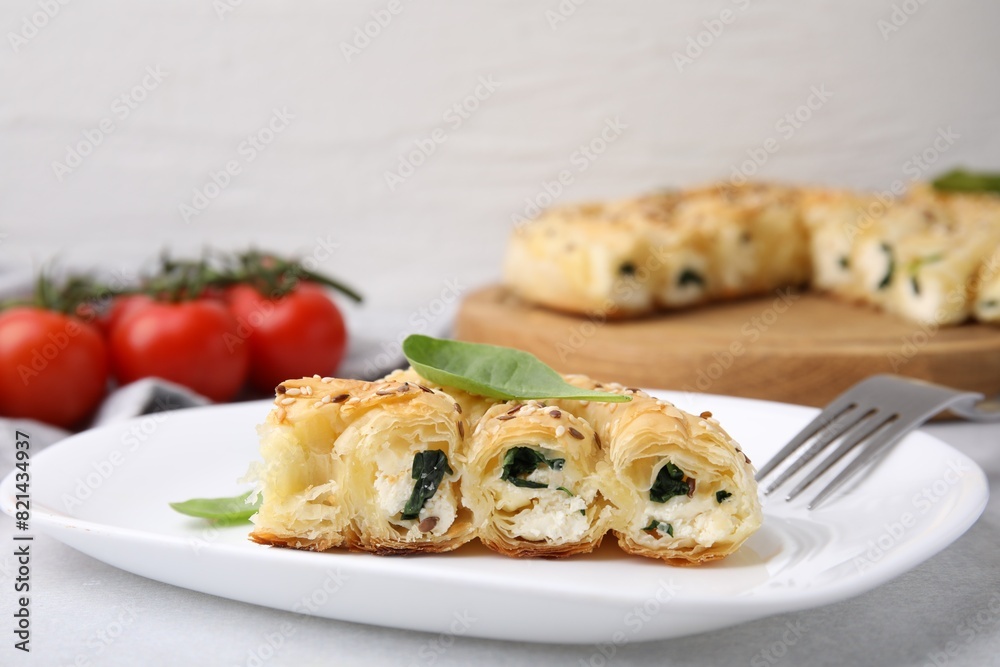 Piece of delicious puff pastry with spinach on light table, closeup Piece of delicious puff pastry with spinach on light table, closeup