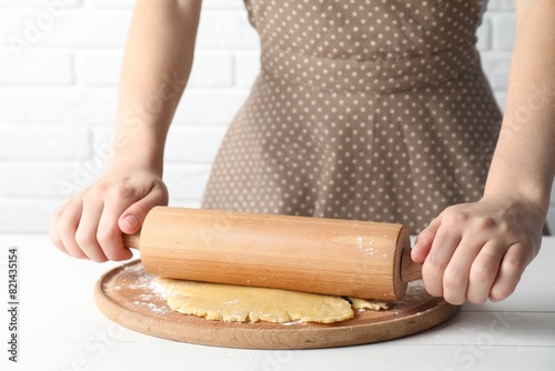 Making shortcrust pastry. Woman rolling raw dough at white wooden table, closeup