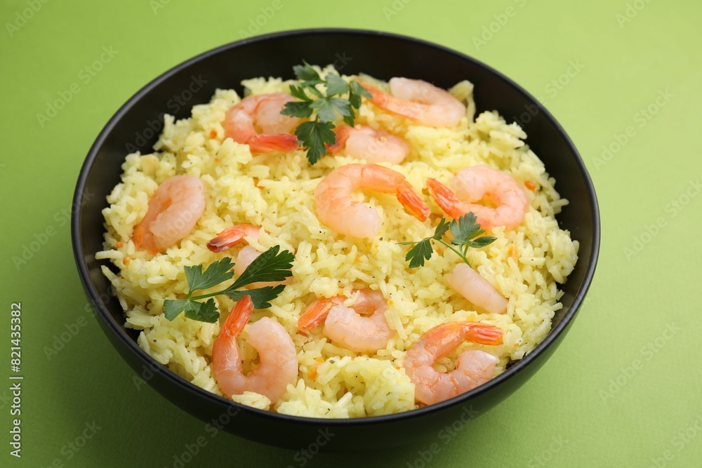 Delicious risotto with shrimps and parsley in bowl on light green background, closeup Delicious risotto with shrimps and parsley in bowl on light green background, closeup