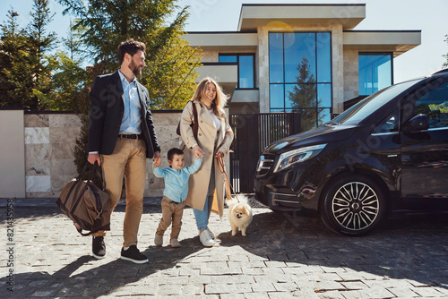 A young family with their son and dog and luggage going by car on vacation for the weekend