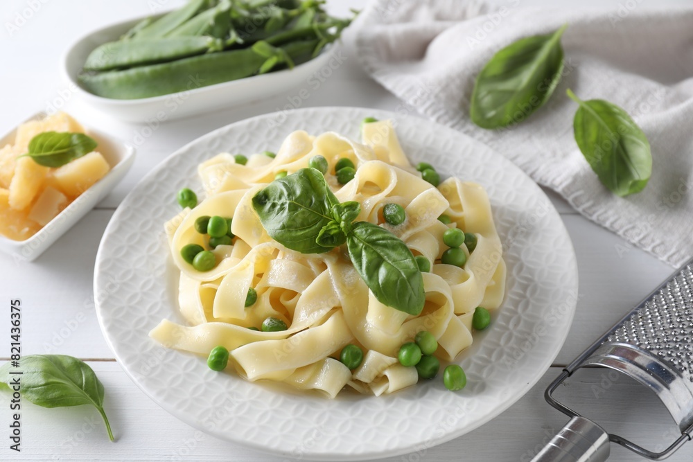 Delicious pasta with green peas and fresh basil on white wooden table Delicious pasta with green peas and fresh basil on white wooden table