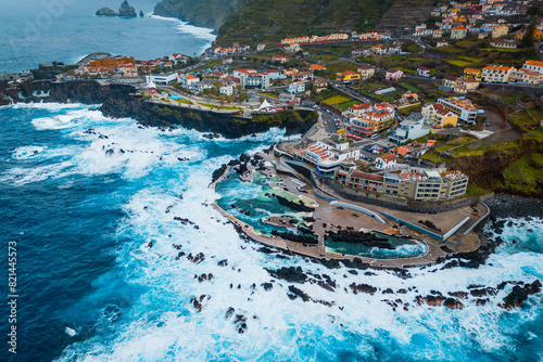 Madeira natural lava swimming pools at Porto Moniz with stormy waves Atlantic ocean, Aerial shot