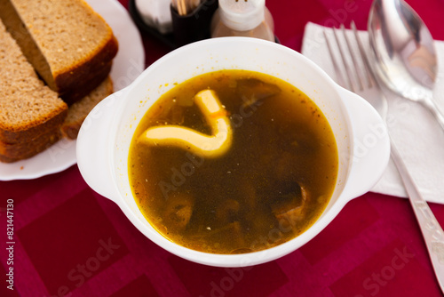 Mushroom soup with mayonaise served on table with bread  serving pieces and napkin.