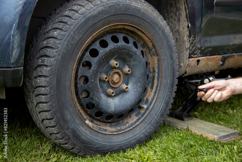 A man meticulously works on the tire of a car, focused on fixing any issues and ensuring it is in perfect condition.