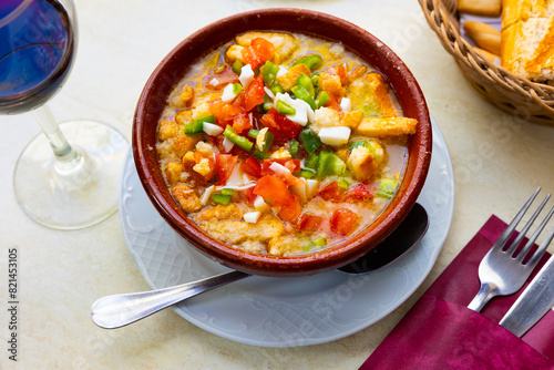 Cojondongo, typical summer dish from Extremadura with chopped tomatoes, pepper and eggs, day-old bread and dressing of garlic, olive oil and water, traditionally served cold in earthenware bowl photo