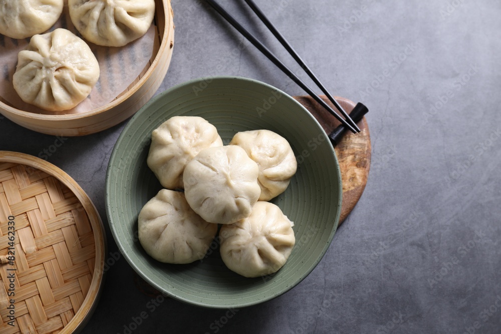 Delicious bao buns (baozi) and chopsticks on grey table, flat lay. Space for text Delicious bao buns (baozi) and chopsticks on grey table, flat lay. Space for text