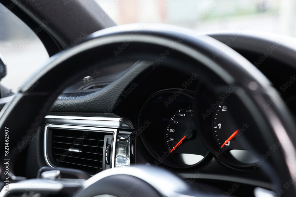 Steering wheel and speedometer inside modern black car, closeup view