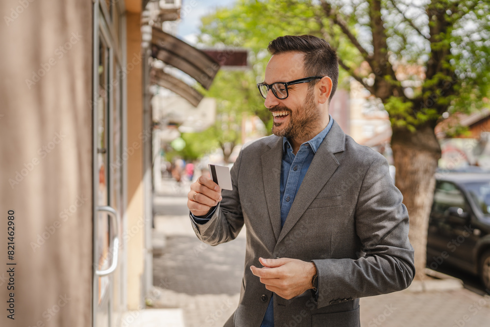 Portrait of adult caucasian man stand and hold credit card on street Portrait of adult caucasian man stand and hold credit card on street