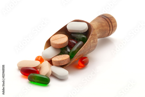 Health care concept. A wooden scoop filled With different Medical Tablets, Pills, and Capsules. Isolated on a white background.