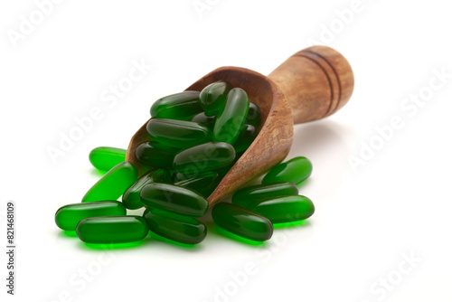 Health care concept. A wooden scoop filled With Vitamin E (Green) Medical Capsules. Isolated on a white background.