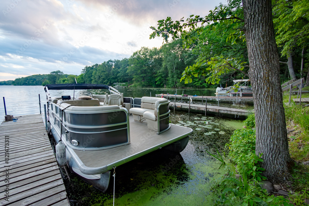 Naklejka premium Looking out onto a Wisconsin northwoods lake as the last rays of sunlight begin to fade. Many pontoon boats have returned from fishing for the evening.