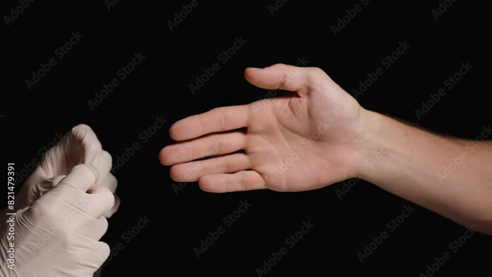 A Doctor's Assistant Helps Put on Latex Gloves for Protection. Black Background. A Doctor's Assistant Helps Put on Latex Gloves for Protection. Black Background.