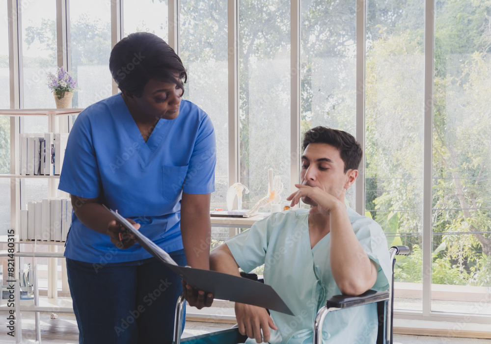 Fototapeta premium Portrait patient caucasian man sit wheelchair with woman nurse carer physical therapist African-American two people talk sign important documents advice feel relax smile happy in hospital room service