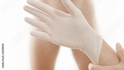 A Female Doctor Prepares for an Examination with an Already Undressed Man in the Background. Bright White Background.