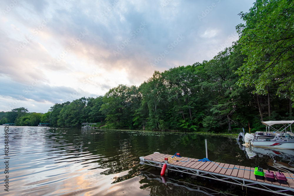 Fototapeta premium Looking out onto a Wisconsin northwoods lake as the last rays of sunlight begin to fade. Many boats have returned from fishing for the evening.